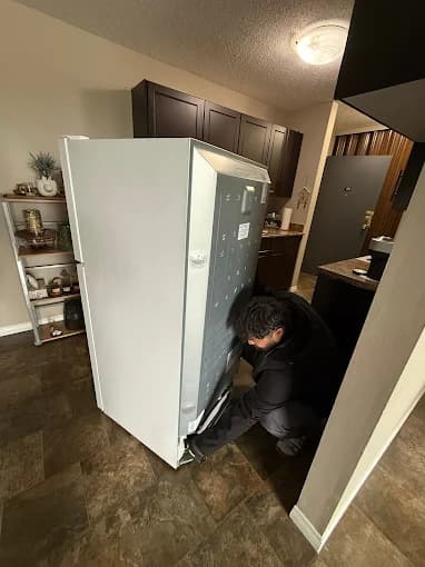 Technician servicing a refrigerator in a customer home